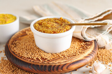Bowl of Dijon mustard with seeds and garlic on white background