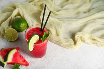 Glass of fresh watermelon juice with lime and mint on white background