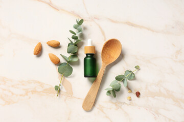 Nuts, wooden spoon and bottle of eucalyptus essential oil on marble background