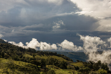 Little white clouds floating over the eastern Andean mountains of central Colombia, in an overcast sunset.