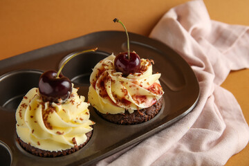 Baking mold with sweet cherry cupcakes on brown background