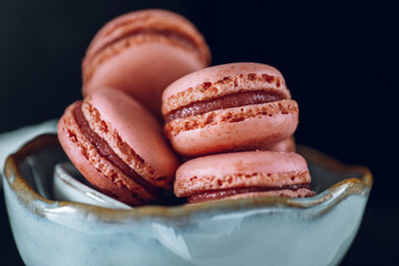 Pink macarons set in a gray ceramic cup on a black background.Low key.Sweets and desserts. French pastries set. Macaron cakes set. 