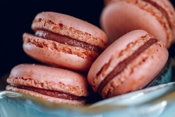 Pink macarons set in a ceramic cup on a black background.Low key.Sweets and desserts. French pastries set. Macaron cakes set. 