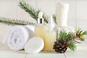 Composition with bottles of essential oil, spa accessories and coniferous branches on light tile background