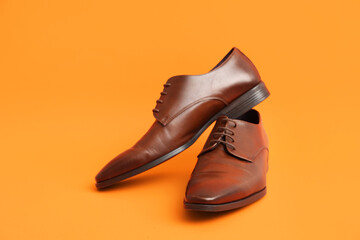 Stylish male leather shoes on orange background