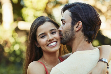 Fototapeta premium Outdoor, couple and happy with kiss in park for bonding, love and affection in Spain. People, relationship and smile for support with care as lovers on break to relax, rest and embrace for date