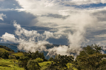 Little white clouds floating over the eastern Andean mountains of central Colombia, in an overcast sunset.