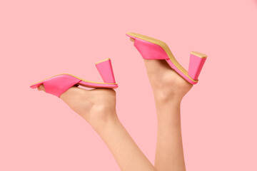 Legs of young woman in stylish pink sandals on color background