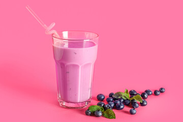 Glass of fresh blueberry smoothie with mint and berries on pink background