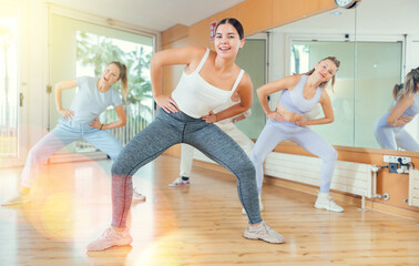 Obraz premium Ordinary active females exercising dance moves in a modern dance studio
