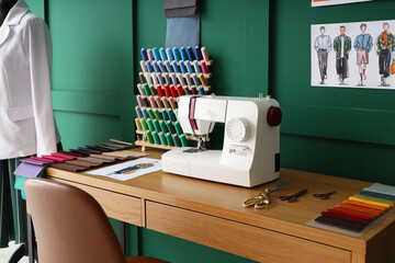 Tailor's workplace with sewing machine, thread spools and fabric samples in atelier