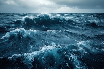 A photo of the ocean with dark stormy waves, cloudy sky, and rough sea in dark blue.