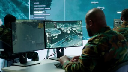 Military crew in a high tech operations command post managing information from radar cctv systems, real time data to support defense missions. Army protocols for national security. Camera A.