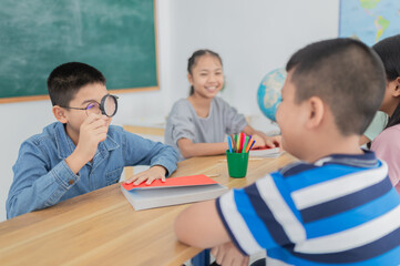 Curious students engage in a classroom activity. A boy examines something with a magnifying glass while his classmates look on with interest. they feeling fun in classroom.
