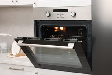Obraz premium Open electric oven with towel in kitchen. Cooking appliance