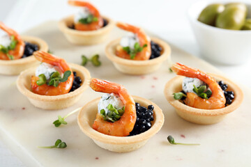 Delicious canapes with shrimps and black caviar on table, closeup
