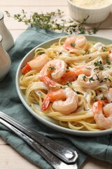 Delicious pasta with shrimps and creamy sauce served on wooden table, closeup
