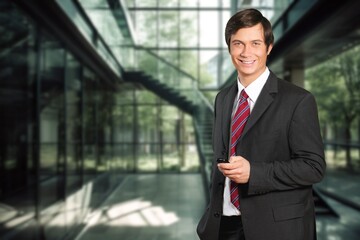 Smiling professional business man in office with mobile cellphone.