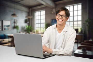 A cheerful male worker answering client typing on laptop