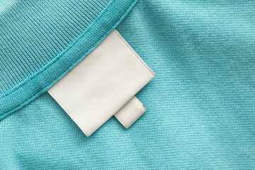 White blank laundry care clothes label on blue shirt fabric background