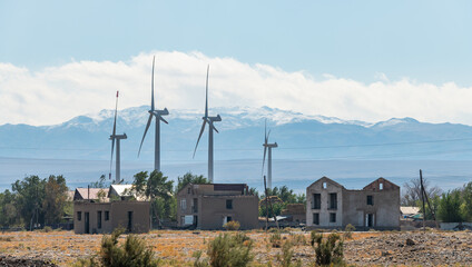 Windmills and dilapidated abandoned houses in Almaty region (Kazakhstan) on a sunny day