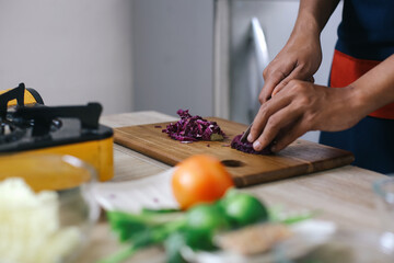 Close Up Man Hands Slicing The Purple Cabbage On Wooden Board. Slicing Ingredients To Make Indonesian Chicken Soup