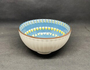 A bowl with unique heart themed carvings, with a black background behind it.