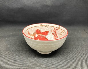 A bowl with unique Chinese carvings, with a black background behind it.
