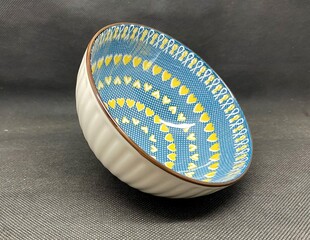 A bowl with unique heart themed carvings, with a black background behind it.