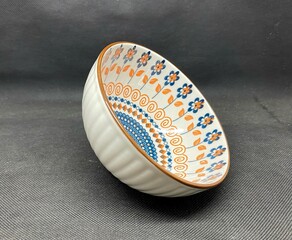 A bowl with unique flower themed carvings, with a black background behind it.
