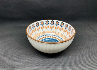 A bowl with unique flower themed carvings, with a black background behind it.