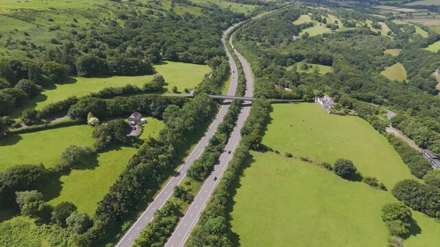 Aerial establishment shot of the A30 road cutting through rural Devon, UK