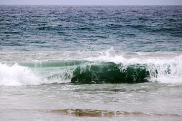 Stormy ocean green-blue waves tossing around a sun shield hat with wide white brims , Pacific Beach, San Diego, CA