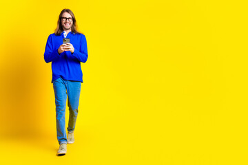 Photo of positive handsome man wear trendy blue clothes go empty space isolated on yellow color background