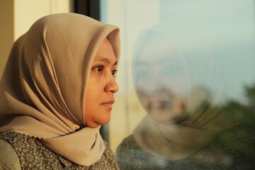 Beautiful woman wearing a hijab in front of the office window waiting for the sunset