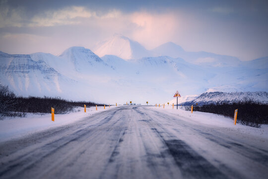 Iceland Ring Road Route 1, during winter, on a beautiful sunny evening, with mountains in the background, asphalt covered with snow,winter time