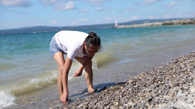 A woman searching for Petoskey stones as waves wash on shore