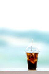 Iced Americano in a take-out plastic cup. Window with a panoramic view