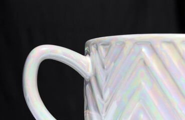 Close-up of a ceramic mug with an iridescent surface abstract against a black background