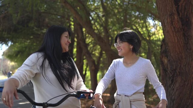 mexican mother and daughter ridding bike at the park