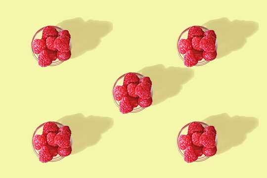 Fresh Raspberries in glass bowls with shadows on a light yellow background, seamless pattern.
