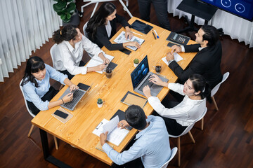 Wide top view of diverse group of business analyst team analyzing financial data report paper on meeting table. Chart and graph dashboard by business intelligence analysis. Meticulous