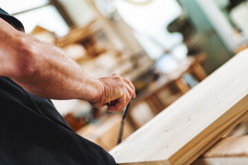 Carpenter working wood plank using hand plane in workshop