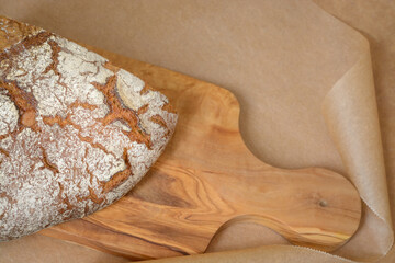 A quarter of rye bread on a wooden cutting board against a background