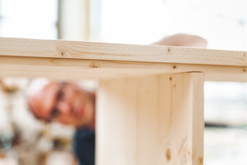 Carpenter inspecting a wooden tabletop in his workshop