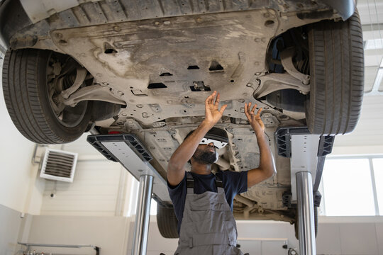 Mechanic using 3D technology inspects vehicle underside for potential malfunctions. Modern automotive garage. Maintenance, repair, and diagnostics concept. High-tech equipment.