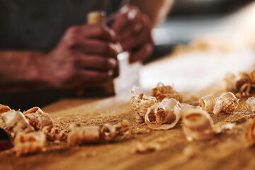Carpenter using hand plane creating wood shavings in workshop
