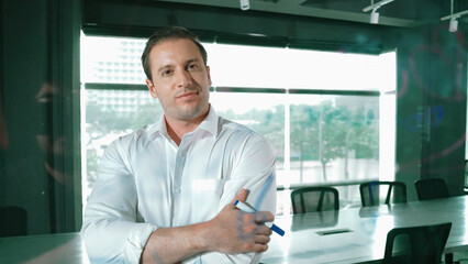Smart businessman thinking about start up project in front of glass board. Smiling male project...