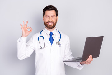 Photo of professional qualified doctor netbook okey symbol wear white coat isolated on grey color background