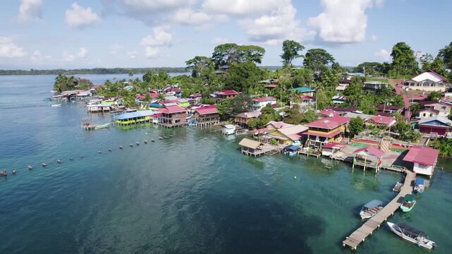 Aerial view showcasing colorful houses along the coast of Bastimentos Island, Panama, in the Bocas del Toro District with lush greenery and clear blue waters.